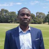 Curtin student, Fatch Kalembo standing on a green oval, looking at camera and smiling