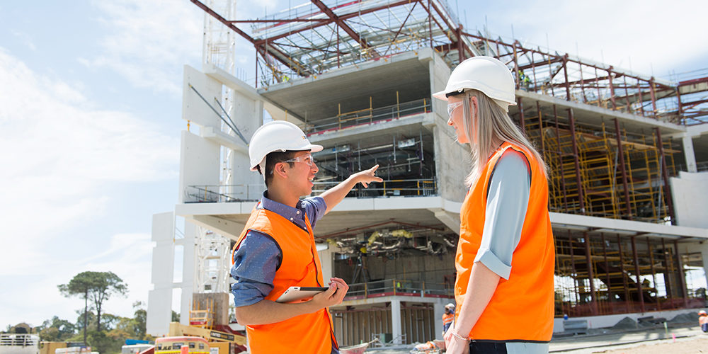 A male and female student standing in front of the Curtin medical centre that is being built