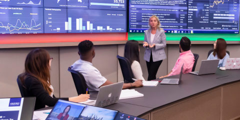 Classroom of students looking at a large screen of analytics